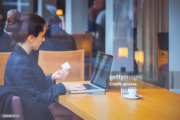 junge geschäftsfrau im café mit einer kreditkarte für online-transaktionen - person surrounded by computer screens stock-fotos und bilder