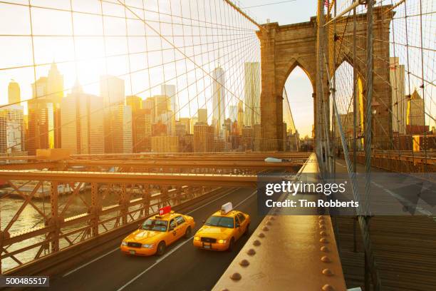 taxis on the brooklyn bridge at sunset in new york - puente brooklyn fotografías e imágenes de stock