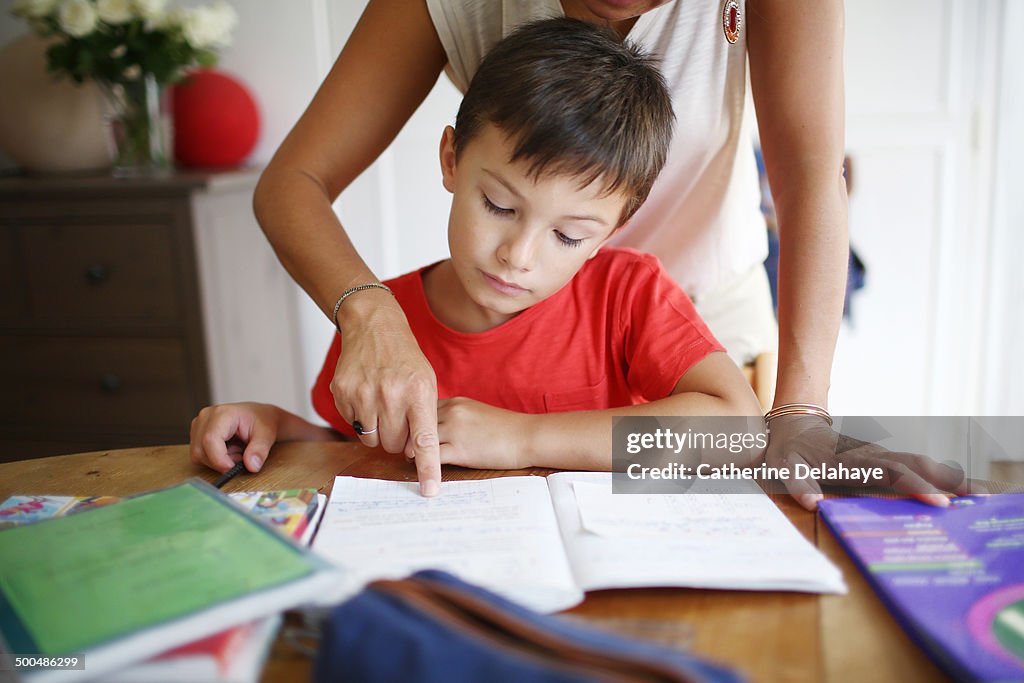 A 7 years old boy doing his homework with his mom