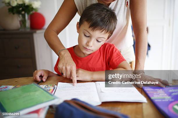 a 7 years old boy doing his homework with his mom - compiti foto e immagini stock