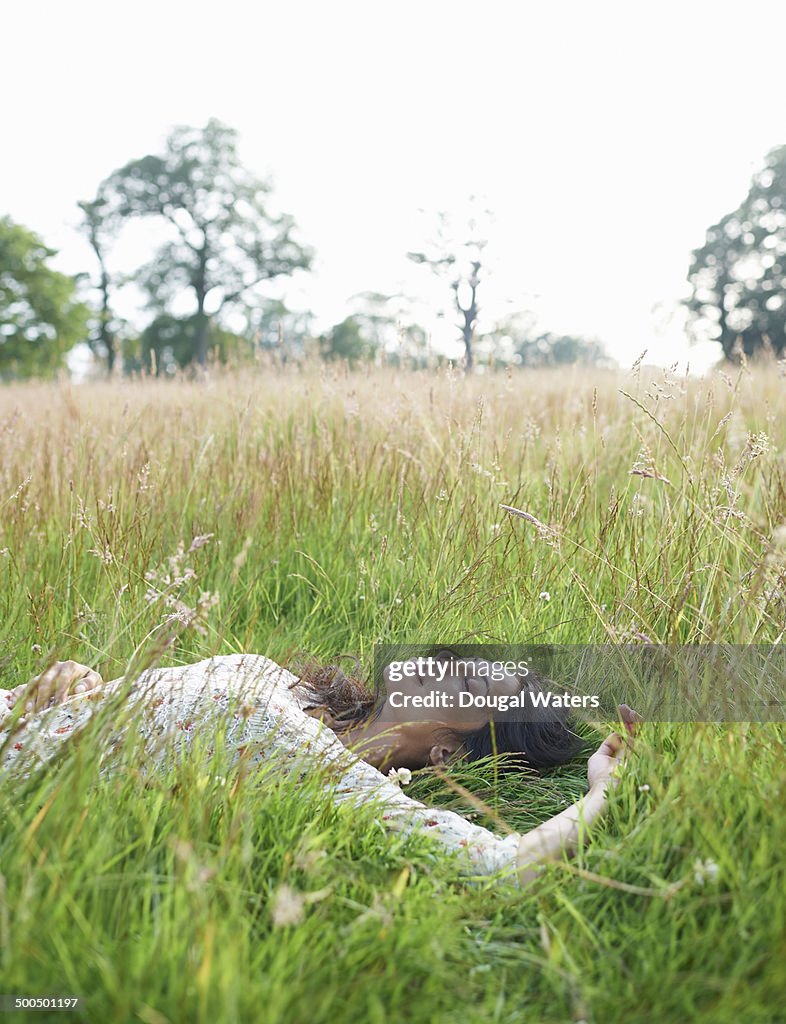 Woman laying in meadow with eyes closed