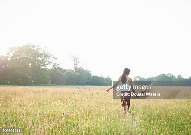 woman walking through grasses in meadow - long hair back stock pictures, royalty-free photos & images