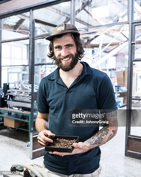 man holding coffee beans in coffee roasting warehouse smiling, portrait - hipster australia stock pictures, royalty-free photos & images