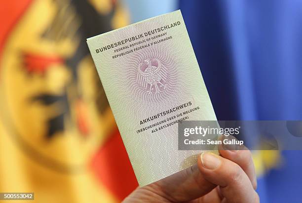 An Interior Ministry employee holds up the new identity card Germany is introducing for asylum applicants on December 9, 2015 in Berlin, Germany. The...