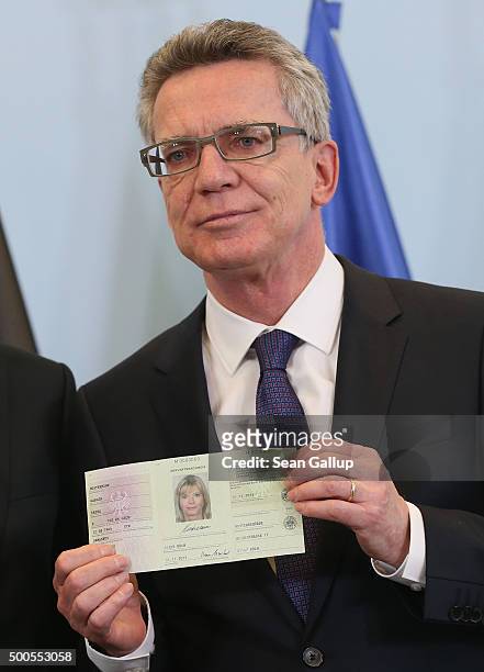German Interior Minister Thomas de Maiziere holds up the new identity card Germany is introducing for asylum applicants on December 9, 2015 in...