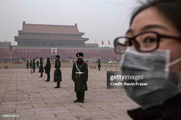 Chinese Paramilitary police officers wear masks to protect against pollution, a rare occurence, as they stand guard before the daily flag lowering...