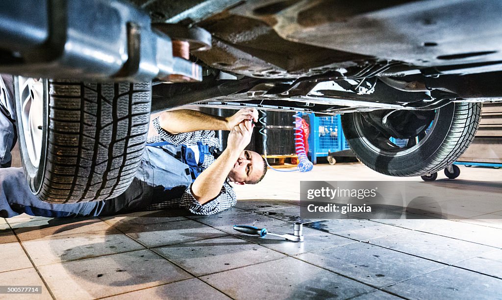 Car mechanic working under a vehicle.