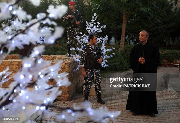 Lebanese police officers stand guard next to Christmas trees outside the Mar Michael church in Beirut's Shiyah neighborhood as a Christian Maronite...
