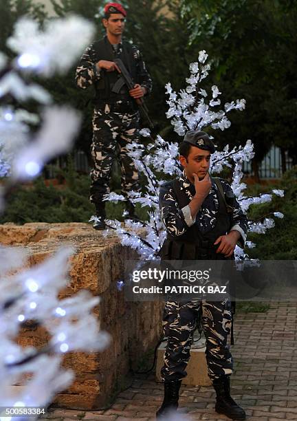 Lebanese police officers stand guard next to Christmas trees outside the Mar Michael church in Beirut's Shiyah neighborhood as they wait for the...