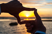 Composition finger frame- man's hands capture the sunset