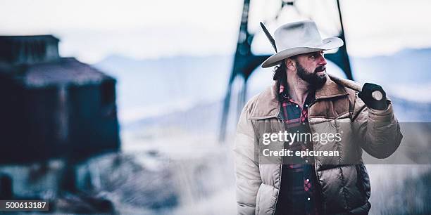 man carrying pickaxe over shoulder walking through western field - pickaxe bildbanksfoton och bilder