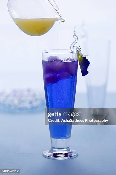 pouring lemon juice on butterfly pea drink - clitoria - fotografias e filmes do acervo