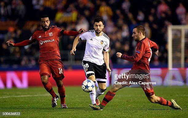 Javi Fuego of Valencia is tackled by Sergi Darder and Alexandre Lacazette of Lyon during the UEFA Champions League Group H match between Valencia CF...