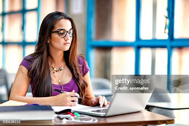 happy hispanic female student using laptop computer in classroom - spanish and portuguese ethnicity stock pictures, royalty-free photos & images