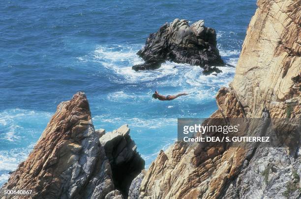 Divers jumping off the cliff called La Quebrada, Acapulco, Mexico.
