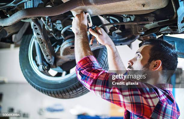 car mechanic working under a vehicle at workshop. - shock absorber stock pictures, royalty-free photos & images