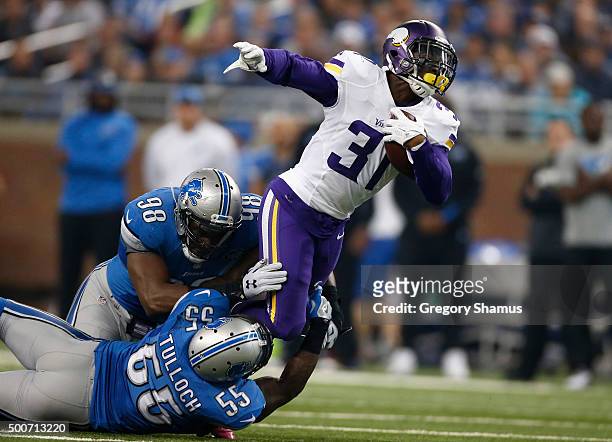 Jerick McKinnon of the Minnesota Vikings is tackled by Devin Taylor and Stephen Tulloch of the Detroit Lions at Ford Field on October 25, 2015 in...