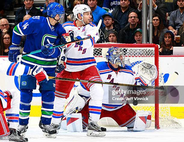 Alexandre Burrows of the Vancouver Canucks and Dan Girardi of the New York Rangers watch a shot by Alexander Edler of the Vancouver Canucks beat...