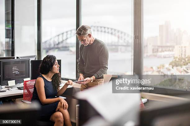 geschäftsleute im büro arbeiten mit einem digitalen tablet - australia technology stock-fotos und bilder