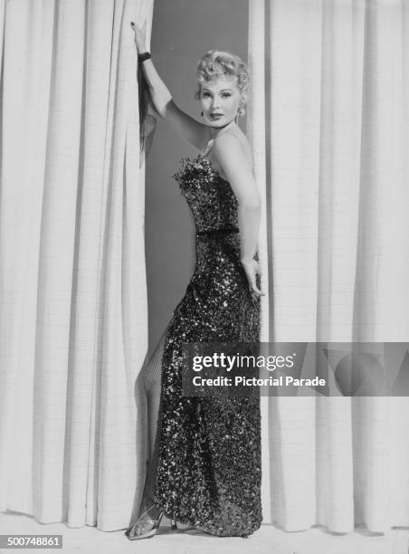 Portrait of actress and socialite Zsa Zsa Gabor, wearing a sequined dress and fishnet stockings, circa 1950-1955.