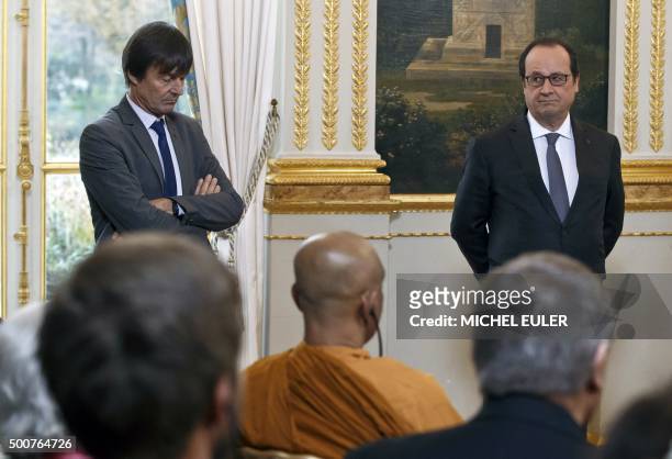 French President Francois Hollande stands on December 10, 2015 at the Elysee palace in Paris next to French environmental activist Nicolas Hulot and...