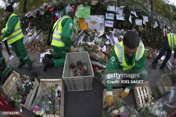 City agents collect objects from the makeshift memorial in tribute to the victims of the Paris attacks outside the Bataclan concert hall in Paris on...