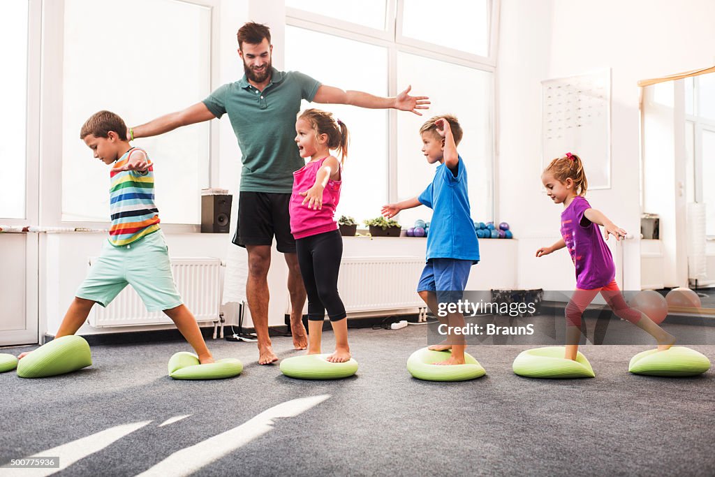 Small children walking on Pilates balls on training class.