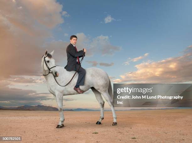 middle eastern businessman riding horse backwards - dobrado de costas imagens e fotografias de stock