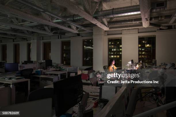mixed race businesswoman working late in office - working late stockfoto's en -beelden