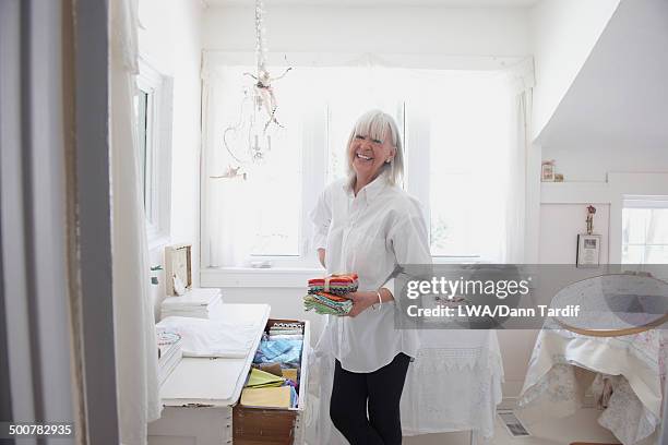 senior caucasian woman putting away baby clothes - fourniture de bureau fotografías e imágenes de stock