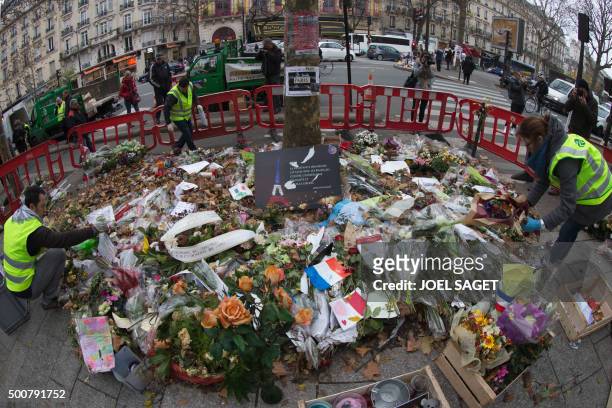 City agents collect objects from the makeshift memorial in tribute to the victims of the Paris attacks outside the Bataclan concert hall in Paris on...