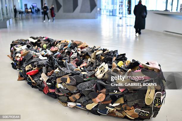 People walk by "Barka" an installation made with shoes by Sislej Xhafa from Kosovo, at the Maxxi museum in Rome on December 10, 2015. AFP PHOTO /...