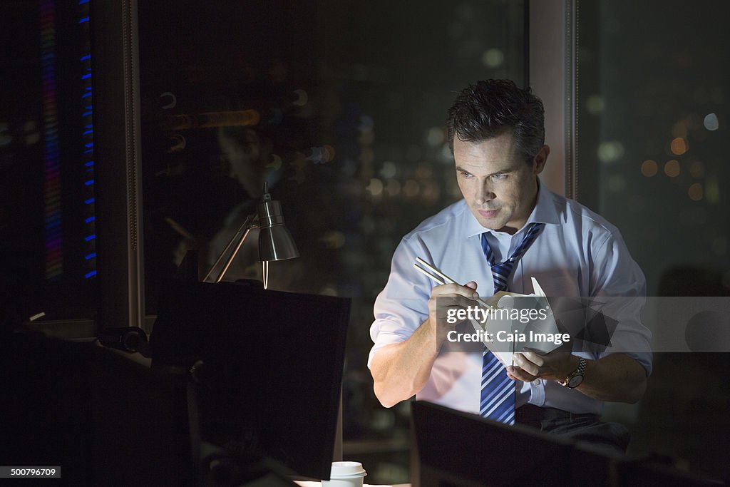 Businessman eating take out food in office at night