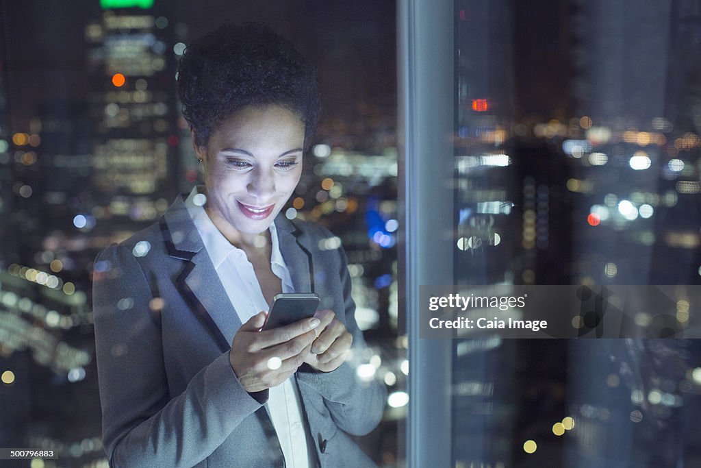 Businesswoman text messaging in urban window at night