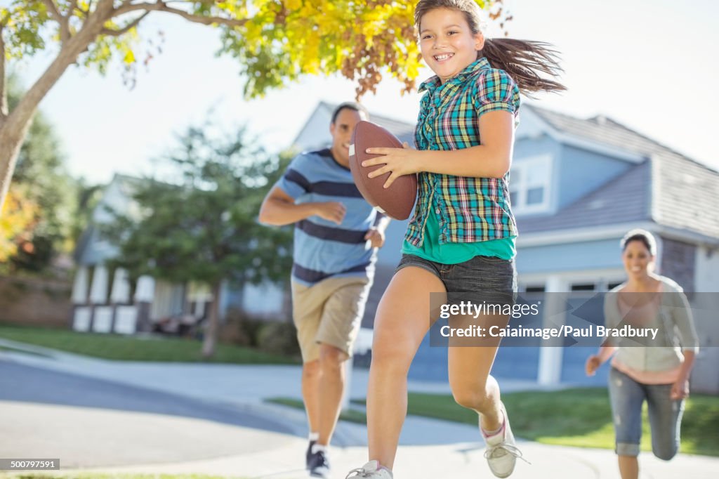 Family playing football in sunny street