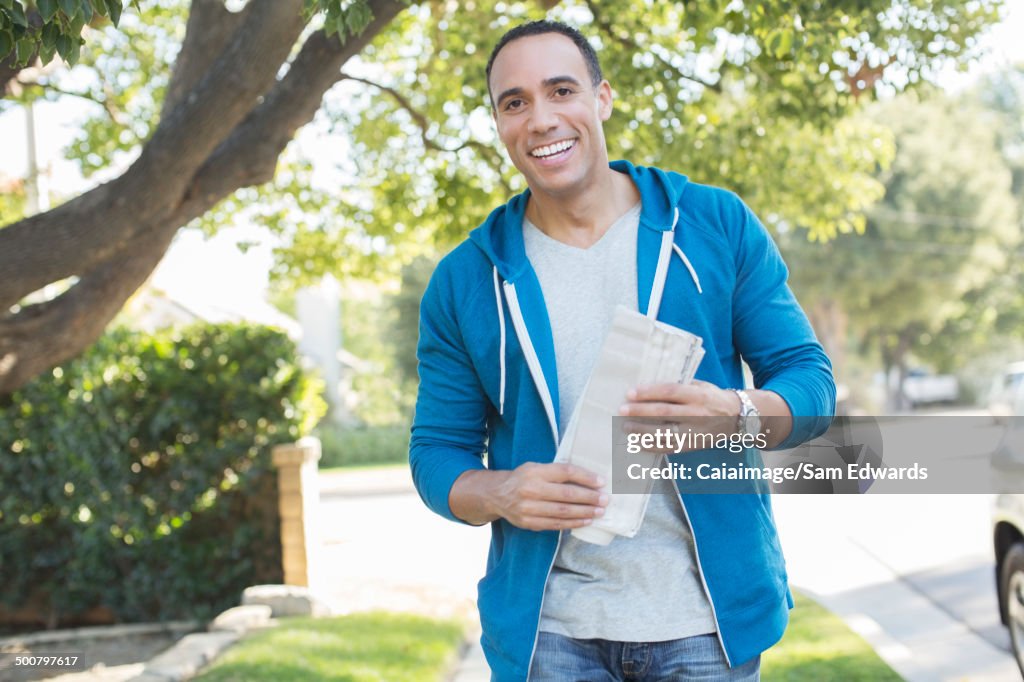 Porträt eines lächelnden Mannes mit Zeitung im Freien