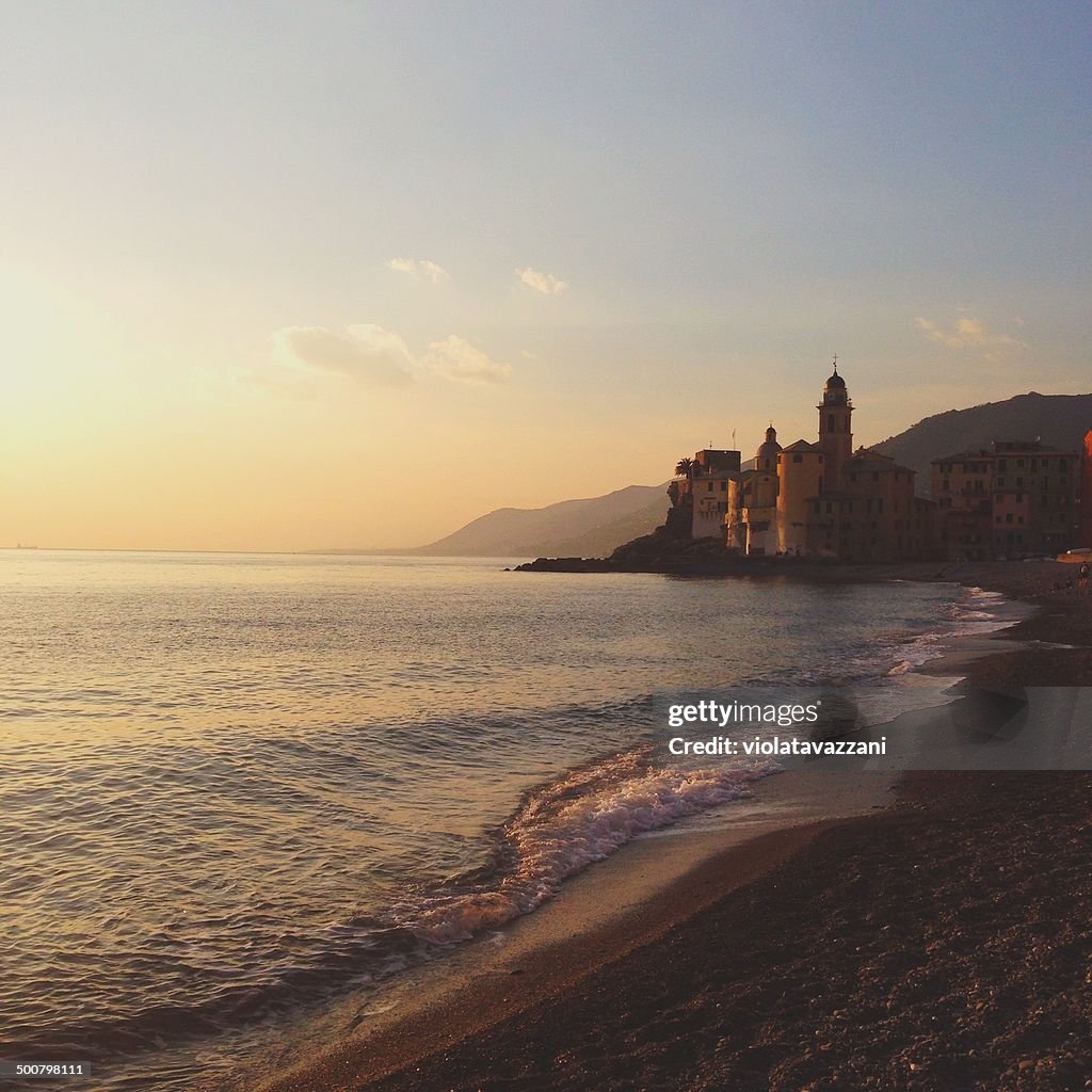 View of town by beach at sunset, Camogli, Italy