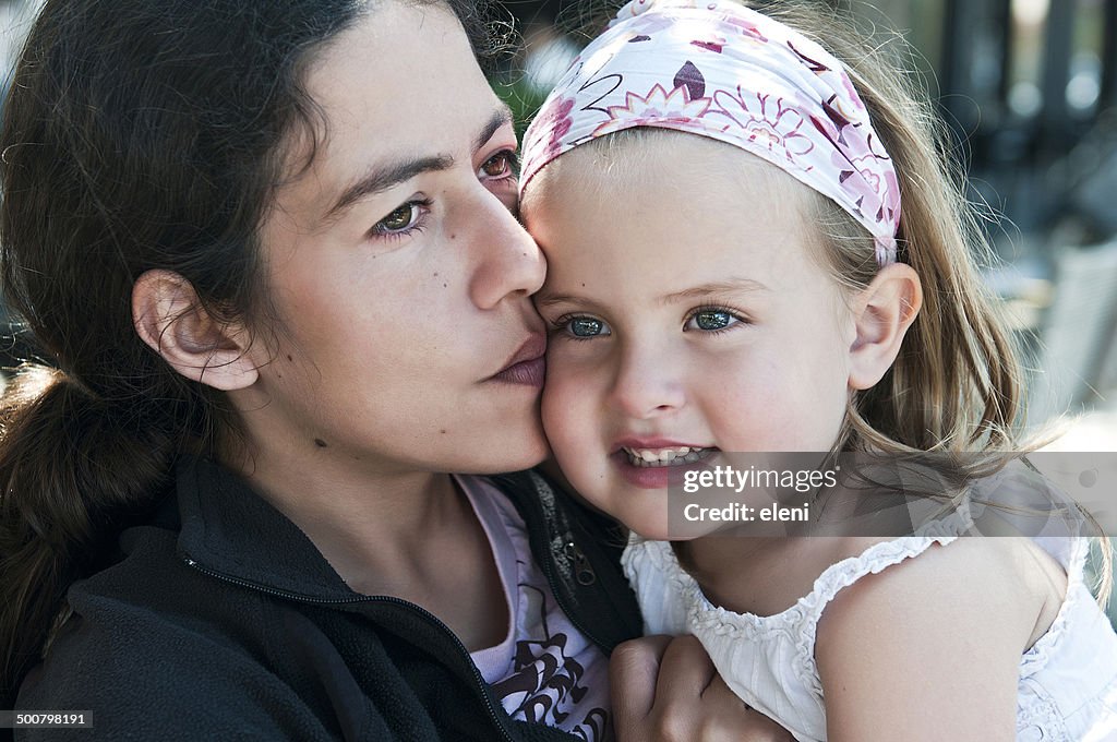 Close-up of Mother hugging and kissing her daughter