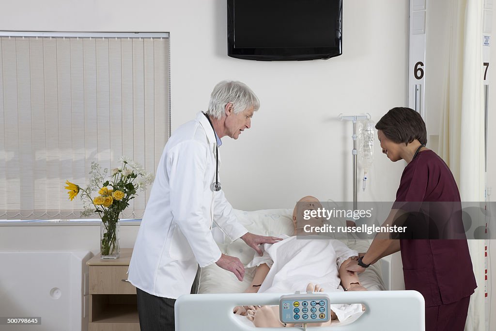 Doctor with nurse examining cpr dummy
