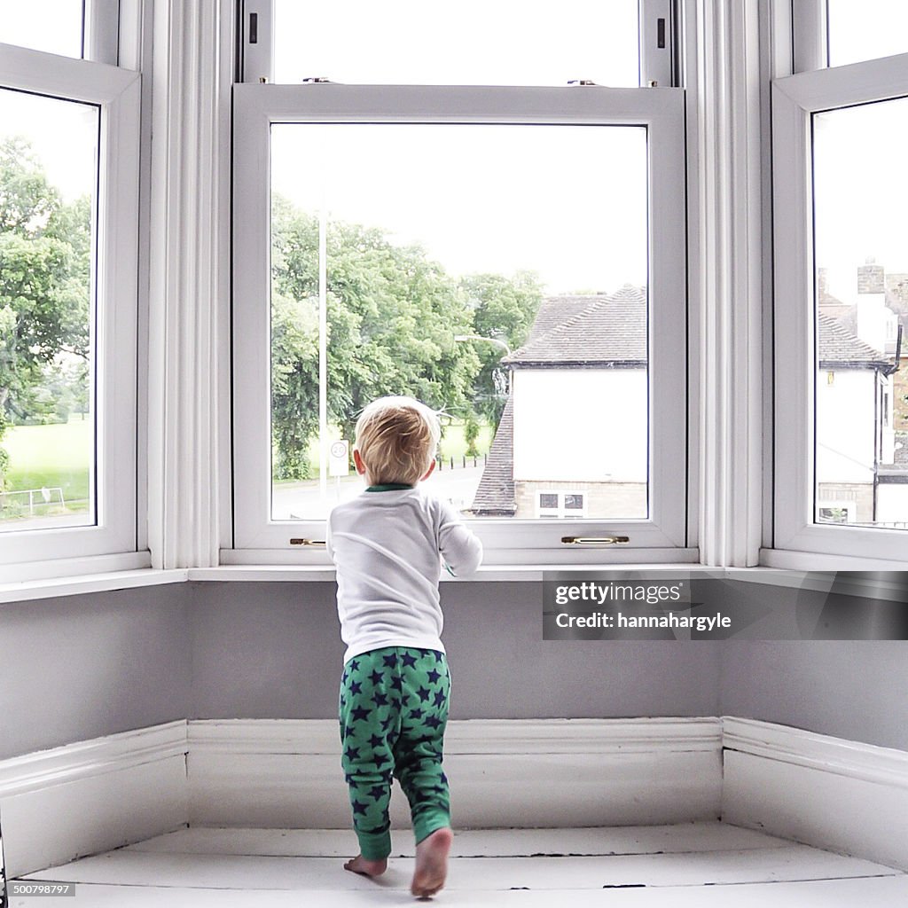 Boy looking out of living room window