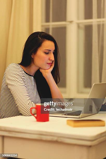 young brunette lesen, am laptop - brunette sitting at desk stock-fotos und bilder