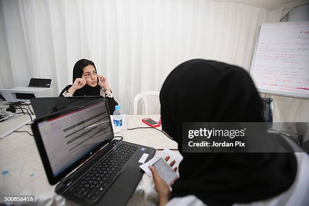 Members of the communication staff for the campagin of a female candiate for the upcoming Saudi municipal elections work hard on contacting and...