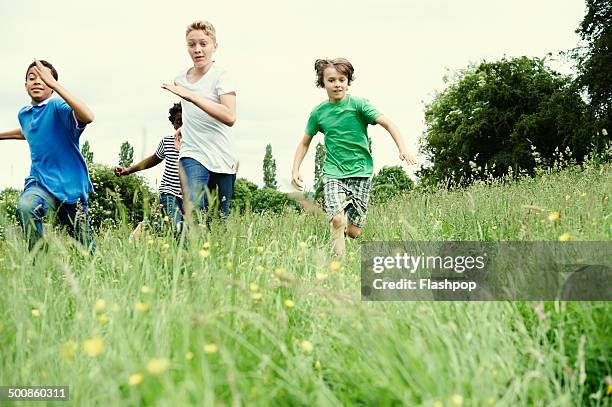 group of friends running through a field - somente crianças imagens e fotografias de stock
