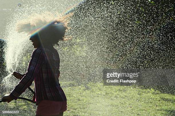 group of friends playing with water - wet hose ストックフォトと画像