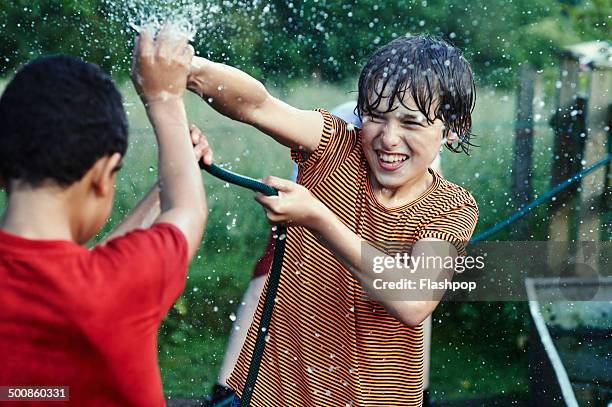 group of friends playing with water - two kids looking at each other stockfoto's en -beelden