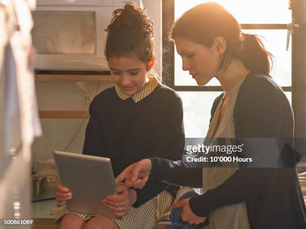 schoolgirl showing her mother home work on an tablet computer - indian girl pointing stock pictures, royalty-free photos & images