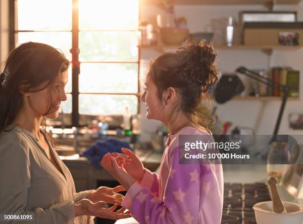 a mother and teenage daughter chatting playfully - stove top stock-fotos und bilder