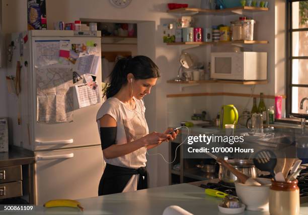 woman in kitchen preparing music for a run - morning kitchen stock pictures, royalty-free photos & images