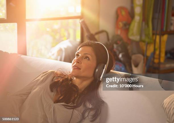 a woman relaxing listening to music on headphones. - protuberanz stock-fotos und bilder