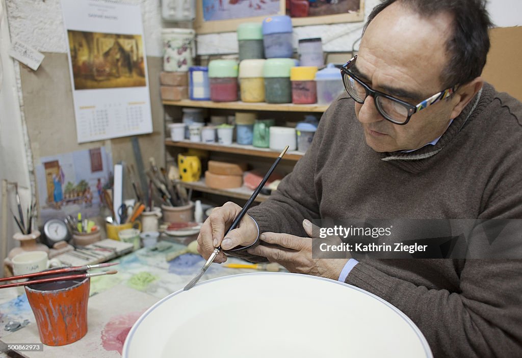 Pottery maker painting ceramic bowl